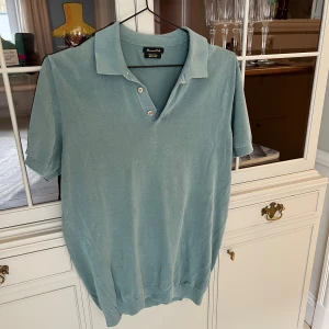 Ljusblå pikétröja från Massimo Dutti - Snygg ljusblå pikétröja från Massimo Dutti i extra fin bomull. Klassisk krage, korta ärmar och tre knappar framtill. Perfekt för en chill och stilren look under vår och sommar.