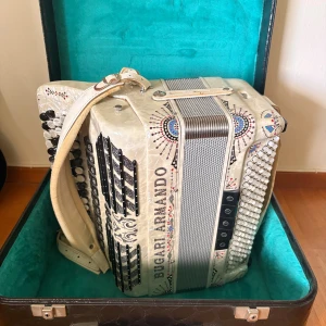 Bugari Armando Dragspel - Exklusivt Bugari Armando dragspel i pärlemor med vackra dekorstenar. Levereras med originalfodral. Mycket knappar och register, i fint skick med endast lättare slitage på remmen. Perfekt för både proffs och entusiaster.