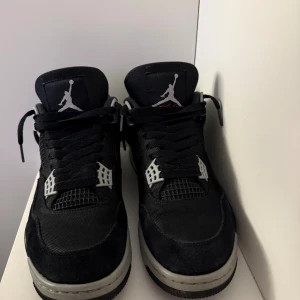 Nike Air Jordan 4 black canvas - Säljer ett par svarta Nike Air Jordan 4 black canvas med grå och vita detaljer. Skorna har klassisk Jumpman-logga, snörning och meshpaneler på sidorna. Ovandelen är i mocka och syntet, sulan är grå med svart yttersula. Perfekta för dig som gillar streetwear. Köpt hos soleplus. 