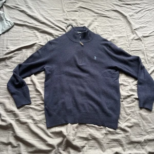 Mörkblå half zip tröja från Polo Ralph Lauren - Mörkblå långärmad tröja från Polo Ralph Lauren med half zip och liten broderad logga på bröstet. Tröjan är i ull och har en klassisk, stilren look med ribbade muddar och hög krage. Perfekt för dig som gillar en clean och tidlös stil. Priset är inte fast!!