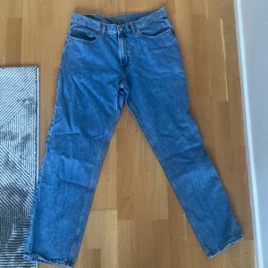 Blå jeans från Vailent baggy modell - Klassiska blå jeans från Vailent i baggy passform. Jeansen har fem fickor, bälteshällor och stängs med knapp och dragkedja. Tillverkade i tåligt denimtyg som ger en tidlös look. Perfekta för dig som gillar enkel och stilren stil.
