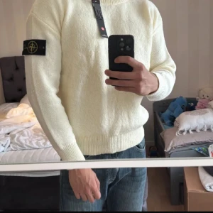 Vit stickad tröja från Stone Island - Säljer en clean vit stickad tröja från Stone Island med klassisk patch på vänster ärm. Tröjan har rund halsringning, ribbade muddar och en relaxed passform. Perfekt för dig som vill ha en stilren och enkel look. Obs den är beige vit gul