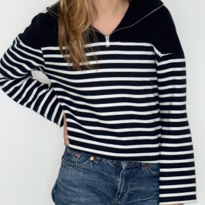 Randig hoodie med dragkedja - Blå och vit randig hoodie med halv dragkedja framtill och huva. Tröjan har lång ärm och är tillverkad i mjukt bomullstyg. 