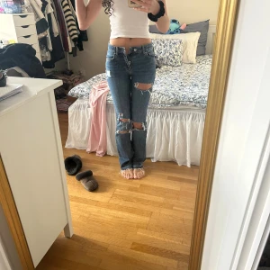  blå slitna jeans midwaist -  Jeansen har flera stora slitningar och hål på framsidan för en riktigt edgy look. Perfekt passform och snygg vintage vibe. Tyvärr för små för mig därav säljer jag. Använda max 5 gånger.