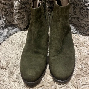 Boots - Snygga olivgröna boots i mocka med rund tå och stabil klack. Dragkedja på sidan för enkel påtagning och en stilren look som passar till många outfits. Perfekta för dig som vill ha en trendig och bekväm sko med lite höjd.