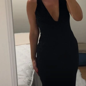 Svart glittrig långklänning med djup v-ringning - Supersnygg svart långklänning med glittriga detaljer och djup v-ringning. Klänningen är ärmlös och har öppen rygg, vilket ger en riktigt elegant och trendig look. Perfekt för dig som vill sticka ut och känna dig extra glam. Från Zara med prislapp