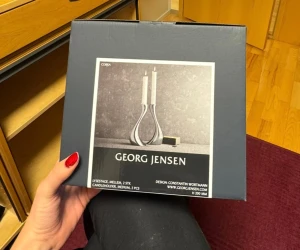 Georg Jensen Cobra Ljusstake, 2-pack - Elegant set med två Cobra ljusstakar från Georg Jensen, designade av Constantin Wortmann. Tillverkade i blankpolerat rostfritt stål, höjd 200 mm. Levereras i originalförpackning, ser oanvända ut och är i nyskick – perfekt för modern inredning.