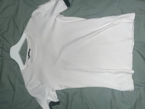 Vit t-shirt från Zara med svarta detaljer - Vit t-shirt från Zara i mjuk bomull med korta ärmar. Ärmsluten har svarta ribbade detaljer som ger en snygg kontrast. Enkel och clean design med rund halsringning, perfekt för en chill och stilren look.