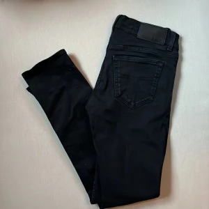 Tiger of Sweden slim fit - Svarta jeansbyxor från Tiger of Sweden i modellen Leon. Snygg, klassisk femficksdesign med svarta sömmar och läderpatch bak i midjan. Jeansen har en smal passform och är tillverkade i mjukt bomullsmaterial med stretch för extra komfort.