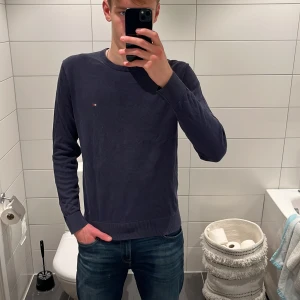 Mörkblå tröja Tommy Hilfiger M - Snygg mörkblå tröja från Tommy Hilfiger i premium bomull. Klassisk rund hals och diskret logga på bröstet. Långärmad modell med ribbade muddar vid ärmslut och nederkant. Perfekt för dig som gillar stilrena och tidlösa plagg. Modellen är 187cm, nypris 1099kr, hör gärna av er om prisförslag!