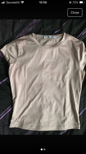 Beige t-shirt från Calvin Klein Jeans - Säljer en stilren beige t-shirt från Calvin Klein Jeans i storlek S. Toppen har rund halsringning, korta ärmar och ett diskret tryck med loggan på bröstet. Materialet är mjukt och har en lätt glansig finish som ger en fräsch look.