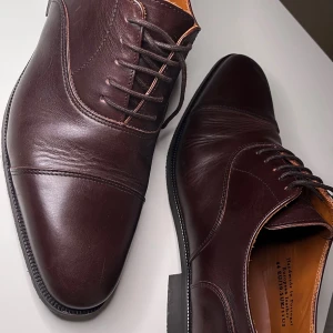 Bruna skinnskor från These Glory Days - Snygga bruna skinnskor från These Glory Days, handgjorda i Portugal. Skorna har snörning, rund tå och platt sula. Tillverkade i europeiskt läder med stilrena sömmar och klassisk design. Perfekta för dig som gillar en dressad look.