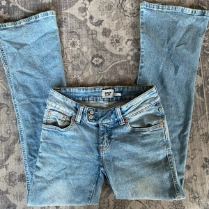 Bootcut jeans - Ett par lågmidjade bootcut jeans från 157 med snygg broderad detalj på bakfickorna och dubbla knappar i midjan, midjemått 38cm rakt över och innerbensmått 79cm 