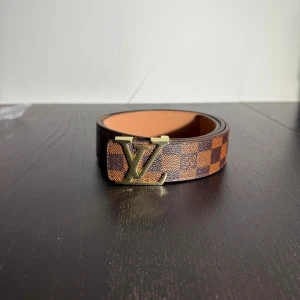 Bälte  - Helt nytt brun rutigt bälte med guldig logga 