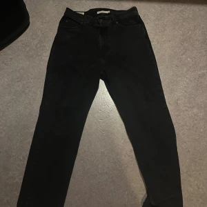 Svarta Levi's 505 jeans slim straight fit - Svarta Levi's 511 jeans med klassisk straight fit och fem fickor. Byxorna har hög midja, knappgylf och Levi's ikoniska läderpatch baktill. Tillverkade i slitstarkt jeanstyg som ger en cool och tidlös look. Perfekta för dig som gillar enkel och clean stil.