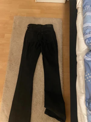 Svarta bootcut jeans - Säljer ett par svarta jeans med bootcut passform. Byxorna har klassisk femficksdesign och är tillverkade i jeansmaterial. Perfekta för dig som gillar en lite vidare siluett nedtill och vill ha en cool look.