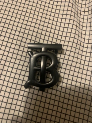 Burberry bälte med TB-spänne - Säljer ett Burberry bälte med klassiskt rutigt mönster i beige, brunt och rött samt ikoniska ryttaren. Bältet har ett svart metallspänne med TB-logga och är gjort i skinn. Perfekt accessoar för att lyfta din outfit. Storlek 105 på midjan.