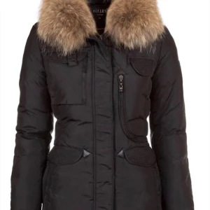 Svart dunjacka med päls från Hollies - Snygg svart dunjacka från Hollies med fluffig päls runt kragen. Jackan har flera fickor med lock, dragkedja framtill och långa ärmar. Perfekt för kalla dagar med sin tjocka och värmande design. Stilsäker look med detaljer som ger extra edge.