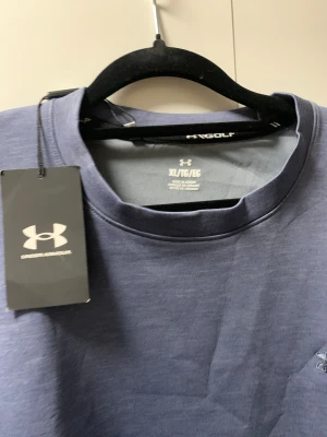 Blå långärmad tröja Under Armour XL - Snygg blå långärmad tröja från Under Armour i storlek XL. Tröjan har rund hals och diskret logga på bröstet. Materialet känns mjukt och är troligtvis bomull eller polyester, perfekt för dig som gillar sportig och clean stil.ny pris ca 799