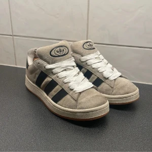Adidas Campus sneakers i beige mocka - Säljer mina adidas Campus i beige med svarta ränder och vit snörning. Älskar de skorna men jag har bara valt att inte använda de mer pga stil. Köpte de nya på Zalando förra året nypris 1349kr 🌟även en helt ny störning till 🍁
