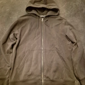 Khakigrön hoodie med dragkedja - Säljer en khakigrön hoodie från Weekday med hel dragkedja framtill och två stora fickor. Tröjan har huva med snörning och är tillverkad i mjuk bomull.