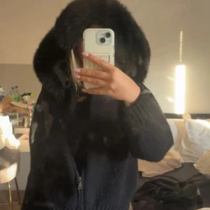 Svart pälsjacka Aleesa - Säljer en svart pälsjacka med superfluffig och bred krage som ger en lyxig vibe. Jackan har dragkedja framtill och ribbade muddar vid ärmslut och nederkant. Perfekt för dig som vill ha en varm och snygg jacka med statement-krage.