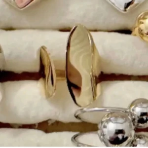 Unika guld ringar  - Säljer flera coola ringar i både guld och silver. En ring har en bred, skulpterad yta i guld med rå textur, medan andra har släta, blanka ytor och några med silverfärgade bollar. Perfekt för dig som gillar att mixa olika former och uttryck.
