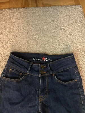 Mörkblå bootcut jeans Buena Vista XS - Snygga mörkblå jeans från Buena Vista i storlek XS. Modellen har bootcut-ben, låg/mid midja. Jeansen är tillverkade i jeansmaterial med kontrastsömmar och dubbla knappar i midjan för extra detalj. Perfekt för dig som gillar en tidlös look. Har använt max 3 gånger.