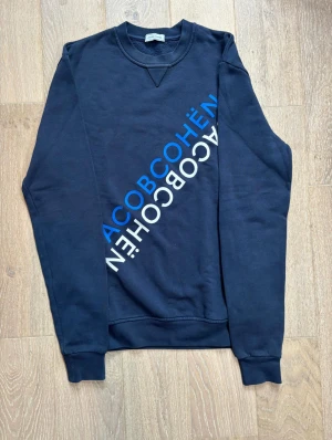 Mörkblå sweatshirt från Jacob Cohën - Snygg mörkblå sweatshirt från Jacob Cohën med diagonal logotyp i blått och vitt på framsidan. Nypris de denna ligger på 4000kr vårt pris är 999kr!!!
