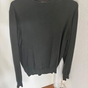 Mörkgrön stickad tröja Oscar Jacobson - Snygg mörkgrön stickad tröja från Oscar Jacobson, tillverkad i Italien. Tröjan har rund hals med ribbad kant och långa ärmar. Enkel och stilren design som funkar till många olika looks. Perfekt för dig som gillar klassiska plagg med modern vibe.