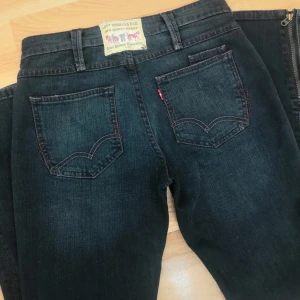 Levi's mörkblå jeans - Mörkblå Levi's jeans med klassiska fem fickor, röda sömmar och dragkedja vid benslut. Snygg tvätt och raka ben. Unik design. Tyvärr inga bilder på då jeansen inte passar mig. Skriv vid frågor💕