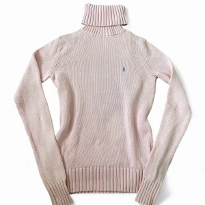 Ljusrosa polotröja från Ralph Lauren | 36 - Säljer en ljusrosa polotröja från Ralph Lauren Sport i storlek S. Tröjan är stickad i 100% bomull och har en ribbad polokrage samt muddar vid ärmslut och nederkant. På bröstet finns den klassiska blå Ralph Lauren-loggan broderad.