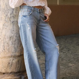 Ljusa blå wide jeans med slitningar - Jättesnygga jeans som endast är använda 2 gånger, typ nyskick. 