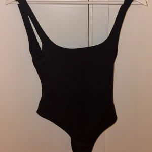 Svart body från Zara - Svart body från Zara med urringning i ryggen. Snygg, klassisk modell som passar perfekt till stranden eller poolen. Tillverkad i ett stretchigt material som sitter skönt på kroppen.
