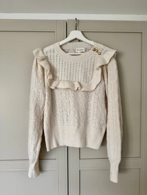 Stickad tröja volanger S guldknappar  - Tröja från Lindex med volanger. Fint skick utan hål och fläckar, lite noppor finns. 