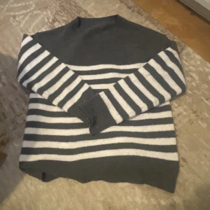 Randig stickad tröja i grått och vitt - Säljer en mysig stickad tröja med breda horisontella ränder i grått och vitt. Tröjan har långärmade ärmar och en klassisk rund hals. Perfekt för att hålla sig varm under kyliga dagar och har en relaxed passform. Storlek xs, knapptttt använd!❤️❤️ inga defekter!