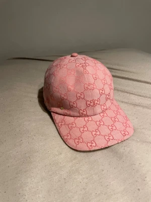 Rosa keps  -  PRIS KAN DISKUTERAS. först till kvarn. Säljer en snygg rosa keps med det klassiska GG-mönstret över hela kepsen. Kepsen har böjd skärm och är tillverkad i ett tygmaterial som känns både lyxigt och trendigt. Perfekt för dig som vill sticka ut med en ikonisk accessoar.