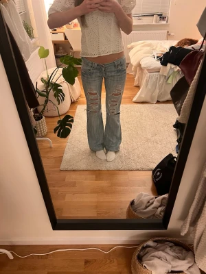 Low waist bootcut jeans med hål - Såå snygga ljusblå lågmidjade utsvängda jeans med hål. Mycket bra skick! Mått finns bland bilderna. Har fått flera höga prisförslag på dem innan därav priset, men det kan alltid diskuteras💕