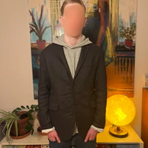 Our Legacy kavaj - Snygg svart kavaj med två knappar framtill och två fickor. Klassisk passform och enkel design som passar till många olika stilar. Kavajen har slits bak och är helfärgad utan synliga mönster. Perfekt för dig som gillar stilrena plagg.