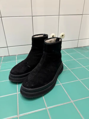 Svarta mockakängor från Gant - Säljer ett par svarta kängor från Gant i mjuk mocka med grov sula och diskret logga på sidan. Insidan är fodrad för extra värme och komfort. Perfekta för kalla dagar och har en stilren, minimalistisk look som passar till det mesta.