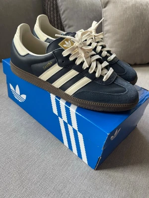 Adidas Samba OG – strl 42 (helt nya) - Helt nya Adidas Samba OG i originalkartong. En av de mest populära sneakersmodellerna just nu. Funkar till exakt allt. Allt og samt blåa snören medkommer.  Skick: Helt nya Storlek: 42  Pris: 1299 kr 