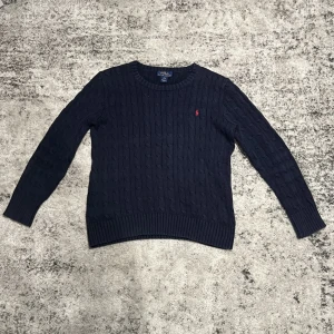 Ralph Lauren cable knit (Läs beskrivning storlek!) - Kabelstickad mörkblå tröja från Polo Ralph Lauren med rund halsringning och lång ärm. Kvaliten på denna tröjan är nästan helt ny men passar tyvärr inte mig! Den är i barnstorlek L (14-16) vilket motsvarar herrmodell ca XS - S!👌 skriv om du är i behov av fler bilder eller bilder på mig i plagget! 📸 Fraktar alltid senast dagen efter beställning!📦