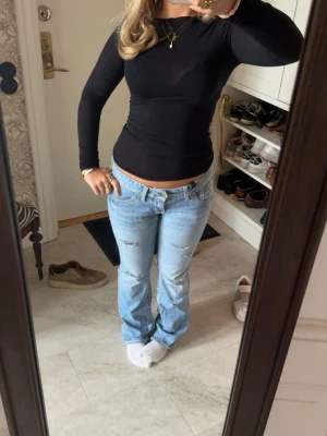 Ljusblå bootcut jeans låg midja - Snygga ljusblå jeans med bootcut och låg midja. Jeansen har slitna detaljer och klassisk femficksdesign. Säljer pga inte kommer till användning men så sjukt snygga. Köpta här på plick och väldigt bra skick