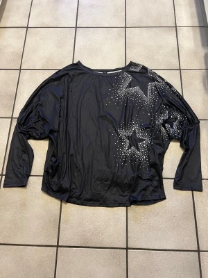Svart långärmad topp med stjärndetaljer - Cool svart långärmad topp med glittriga stjärnor i silverfärgade nitar på framsidan. Oversized passform och rund halsringning. Perfekt för dig som vill sticka ut lite extra.