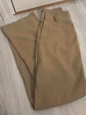 Beiga kostymbyxor från SHEIN i storlek xs, men skulle säga att dom är en stor xs  - Säljer ett par beiga kostymbyxor från SHEIN i storlek XS. Byxorna har hög midja, vida ben och klassiska bälteshällor. Perfekta för en clean och stilren look. Materialet känns mjukt och lätt, vilket gör dem sköna att bära hela dagen.