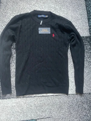 Svart stickad tröja Polo Ralph Lauren - Svart med röd logga stickad polo Ralph lauren tröja storlek S. aldrig använd, priset kan diskuteras
