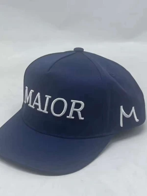 Mörkblå keps med MAIOR-brodyr - Snygg mörkblå keps med vit brodyr där det står 'MAIOR' framtill och ett M på sidan. Klassisk sexpanel-design med böjd skärm. Perfekt accessoar för en streetwear-look. Materialet är troligtvis bomull eller polyester.