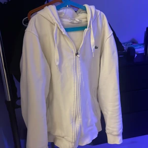 Vit hoodie med dragkedja från Lacoste - Säljer en clean vit hoodie från Lacoste i storlek M men passar även Strlk S helt fri från defekter säljer pga inte passar längre 