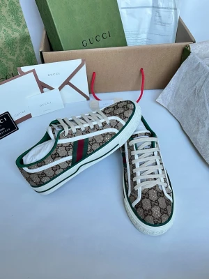 Gucci GG Supreme sneakers med ränder - Gucci sneakers i GG Supreme canvas med gröna och röda ränder på sidorna. Låga med vita snören och detaljer i grönt och vitt. Klassisk logotypmönstrad design och vit sula. Perfekta för dig som vill sticka ut med lyxig streetstyle.