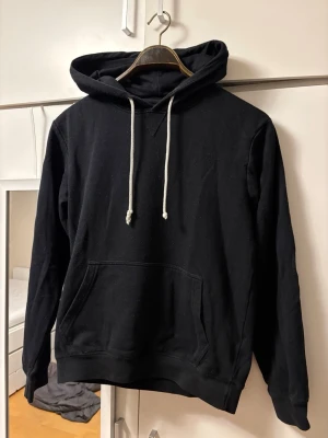 Hoodie med snören - En klassisk svart hoodie med vita snören. Hoodien har en avslappnad passform och är tillverkad i mjukt bomullstyg. Perfekt för en chill och stilren look. Märke Pier one, bra skick storlek xs, tveka inte för att höra av dig om frågor!